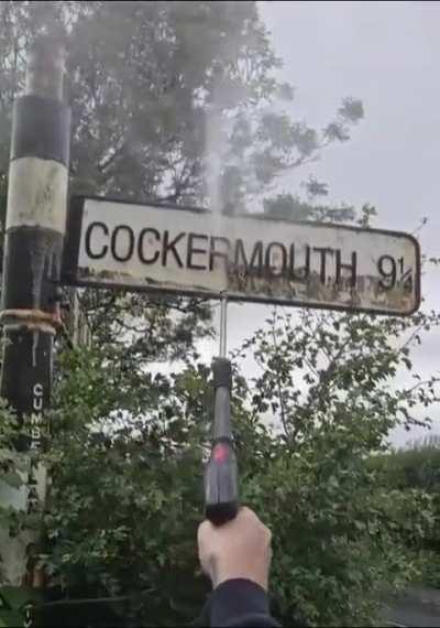 Pressure washing a road sign of an English town 