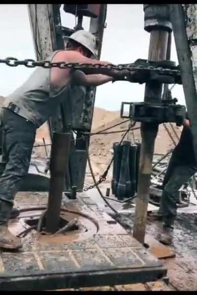 Oil rig worker ”throwing the chain” (a dangerous method of connecting the drill pipes)