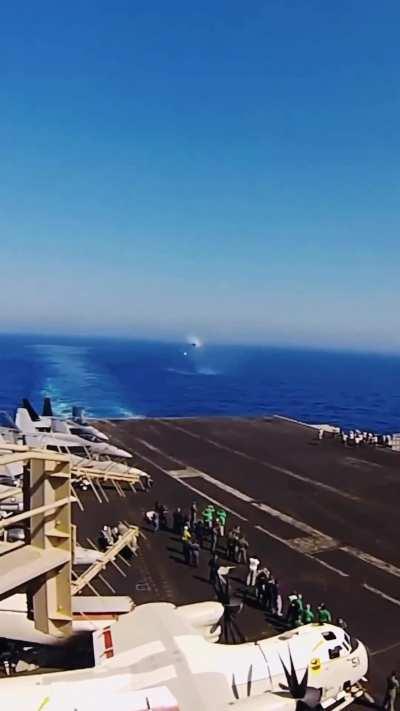 Boeing F/A-18 Super Hornet going supersonic past an aircraft carrier