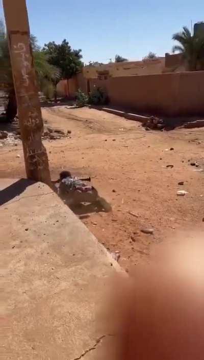 RSF fighter in Sudan fires RPG while laying behind cover 