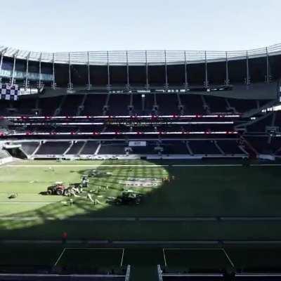 A modern football stadium being transformed for a rugby game