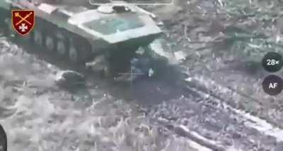 Two Russian soldiers lying near a BMP shoot themselves in sequence