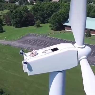 Drone captures a man sunbathing on a wind turbine