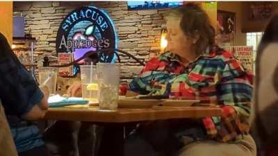 Woman feeding her dog (in a restaurant) like a bird.