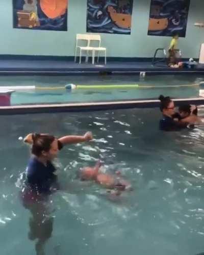 Instructor teaches baby how to swim