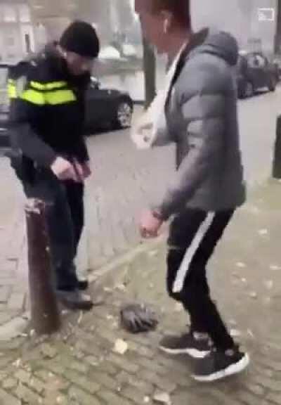 Dutch police officer tying the shoelaces of a man with a broken arm