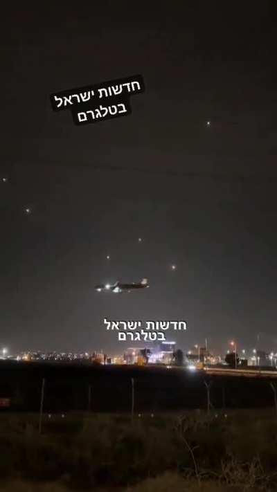 A plane landing while Hamas rockets are being intercepted, Israel