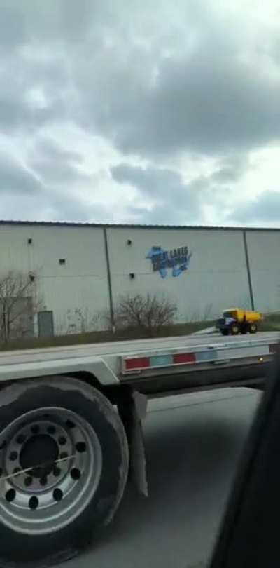 Big truck pulling little truck down the highway