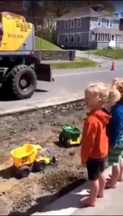 Bro construction workers fills kids truck with big machine.