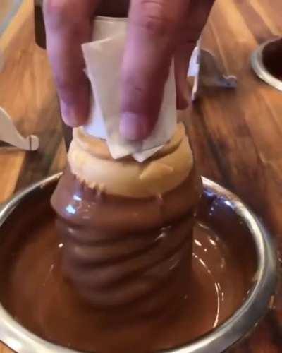 Dipping ice cream into chocolate.