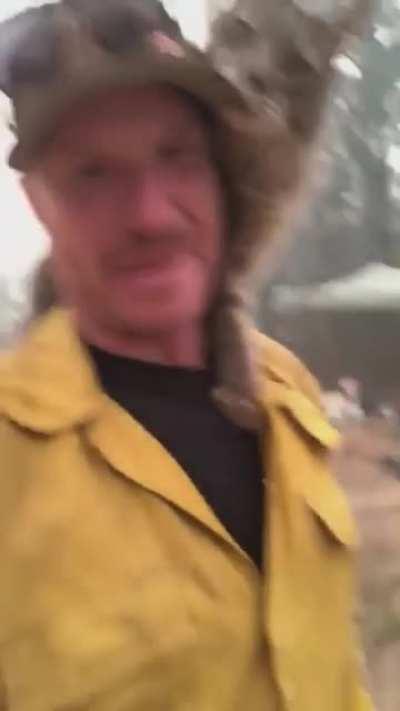 A firefighter being thanked by a very friendly cat after rescuing it from a wildfire