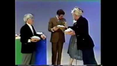 Moe Howard of the Three Stooges gives a pie throwing lesson on a talk show, 1970s