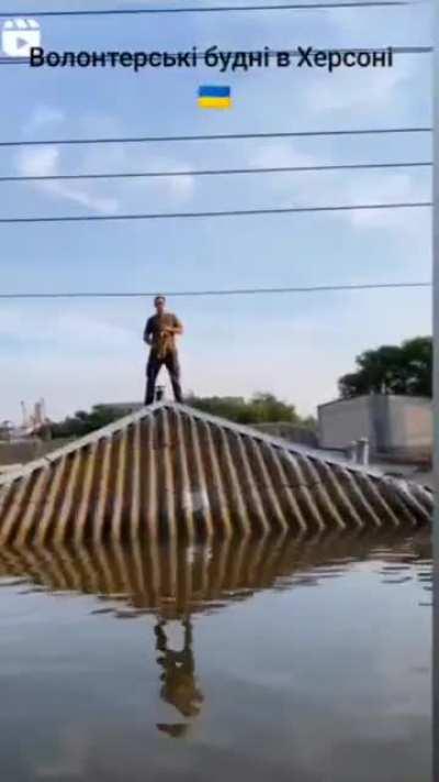 Kherson. The volunteer performs the National Anthem of Ukraine from the roof of the house that went under the water. Ukrainians are unbreakable.