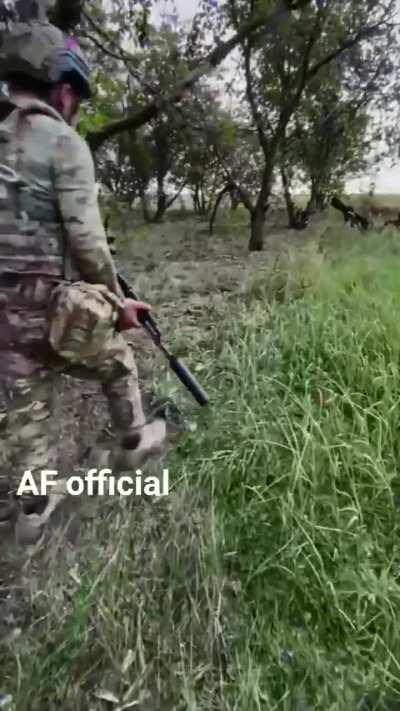 Ukrainian troops patrol past destroyed Russian equipment in the woods.