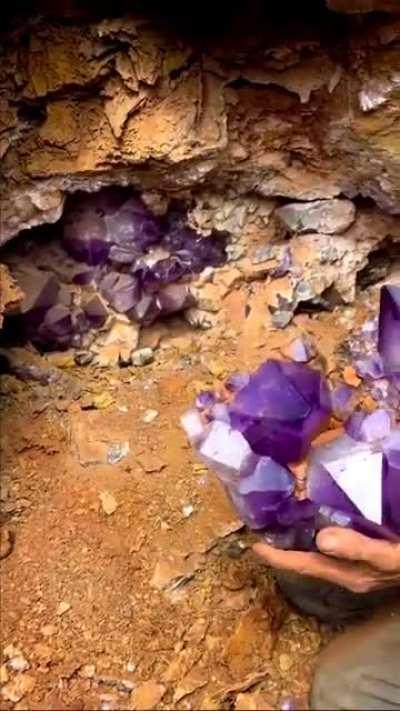 Extracting Amethyst crsytals, a violet variety of quartz, from an open cavity in ground