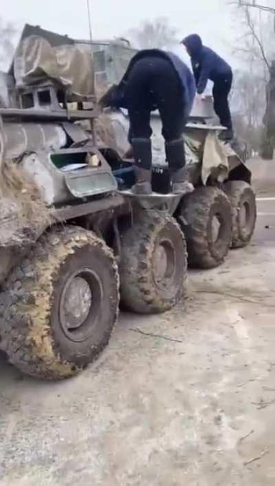 Somewhere in Ukraine, locals find an abandoned BTR (possibly mechanical failure) and promptly proceed to drain diesel from it.