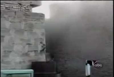 [Iraq] After an Iraqi insurgent falls in between two buildings, a Marine throws a hand grenade in the gap, then uses his rifle to kill him. Fallujah, Iraq. November 2004. 3/5th Marines.