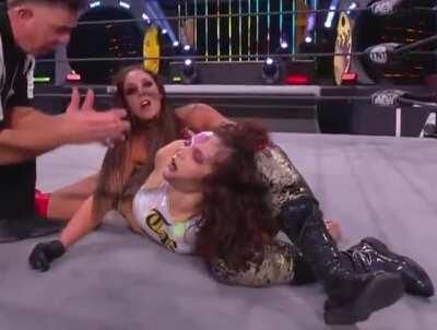 Britt Baker showing Thunder Rosa's unconscious face to the camera