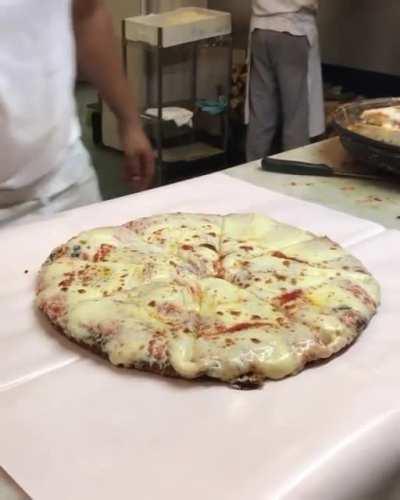 This extremely cheesy pizza being wrapped up like a present.