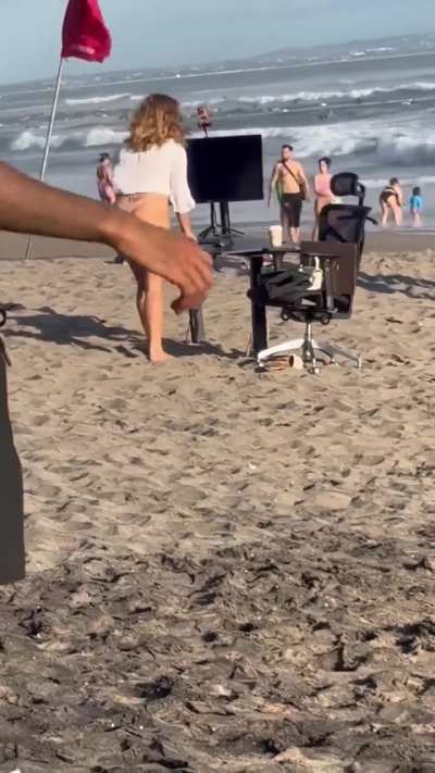 girl pretends to setup office on the beach for attention