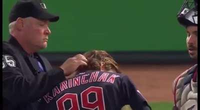 Umpire comforts sad pitcher.