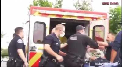 Cop punches a man on a stretcher being put in an ambulance