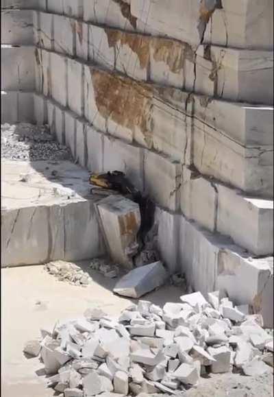 An Excavator in a Quarry Removing an Enormous Slab of Marble