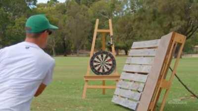 The dude bounces a dart off two pallets and hits the bullseye