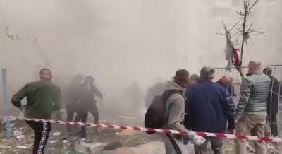 Onlookers scatter as more of the Belograd building collapses during rescue efforts. 