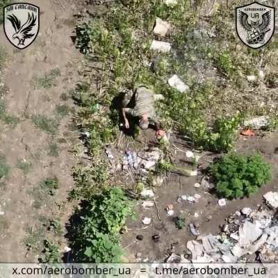 A Ukrainian drone drops munitions on a Russian soldier carrying multiple water bottles. He falls, then eventually gets up and moves into a dugout, where more grenades follow.