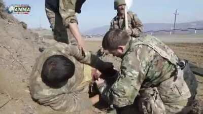 2 wounded Azerbaijani soldiers treated by Armenian soldiers on site and then transported to a hospital while a white flag is being waved.