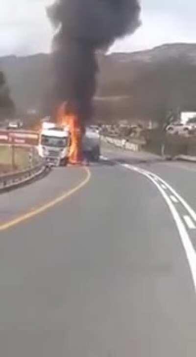 Houwhoek, Western Cape, South Africa. A man leaps into the fire after crawling back up the embankment he drove down, after hitting the truck.