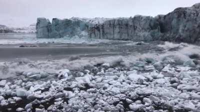 Tourists watch and scramble for cover as a huge chunk of the Breiðamerkurjökull glacier calves. The scale is hard to imagine until you see the waves