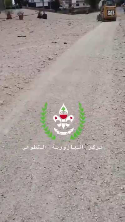 Lebanese civilians filming the debris, while an incoming rocket falls behind him