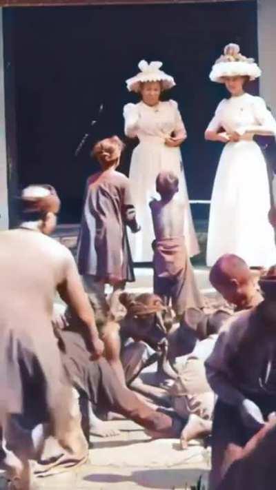 Daughter (right) and wife (left) of French Governor-General Paul Doumer throwing small coins and grains in front of Annamite children in French Indochina (today Vietnam), when it was a French colony, filmed by Gabriel Veyre in 1900.