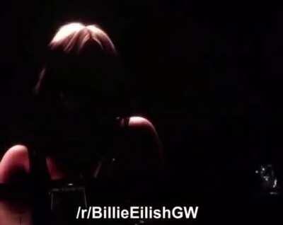 Billie Eilish taking her top of at a live show