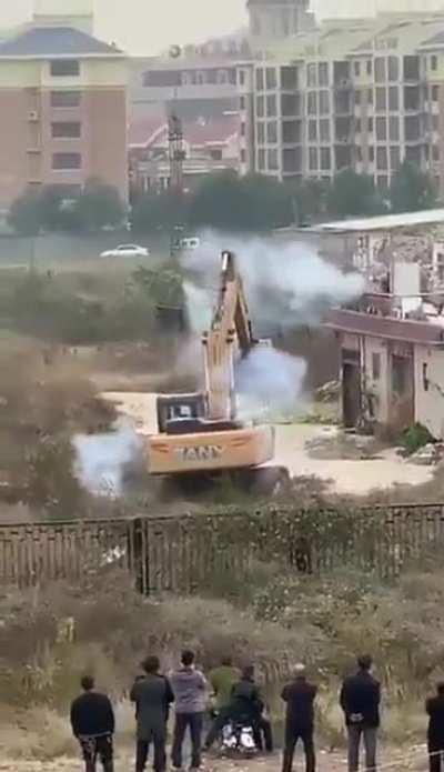 Dude fights off an excavator sent to demolish his building with firework.