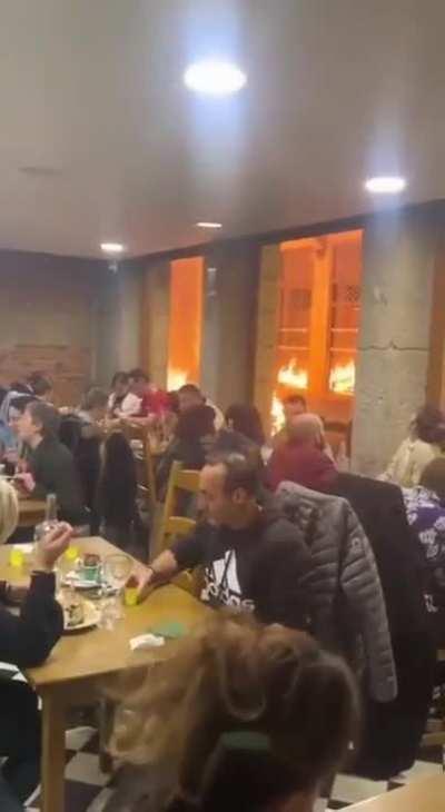 French scene : during strikes against pension's reform, some customers are eating in a restaurant while everything is burning outside