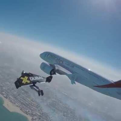 Man with a jetpack, flying next to a plane