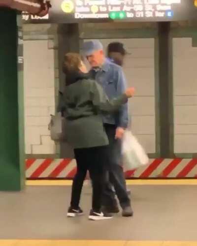 Old couple dancing together at the train station.