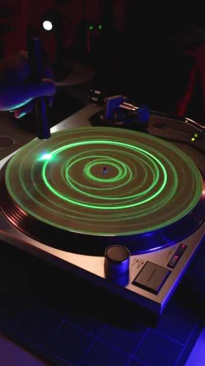 Someone playing with a laser pointer on a glow in the dark record cover.