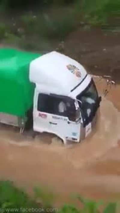 A truck driver successfully passes a flooded way