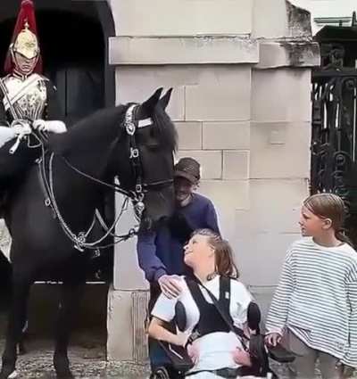 Tourists get approval for a photo opportunity from guard on horseback and the guard makes it an unforgettable moment