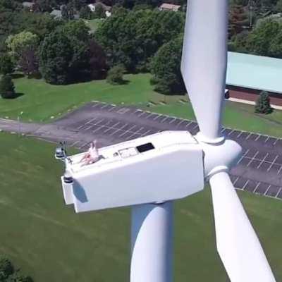 Drone captures a man sun bathing on a wind turbine with no safety on