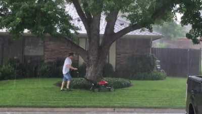 Lightening, check. Large tree, check. Holding onto metal object, check. Neighbor mowing in the rain, check.