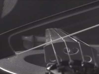 Violin string being driven by a bow in slow motion.