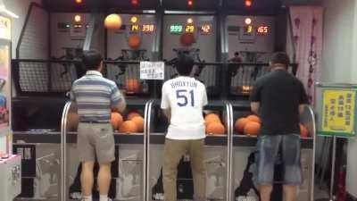 Asian dad locked in on a basketball arcade game