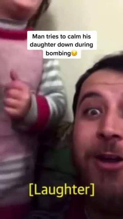 Super dad calming his daughter and making her laugh while the country is getting bombed.