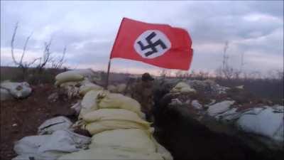 Azov Battalion in Ukraine firing some sort of LMG with a waving Nazi flag.