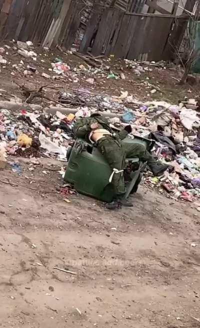 Ukrainian soldier in Mariupol 2022 films the corpse of a Russian soldier slumped on a trash can.